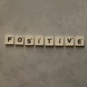 Scrabble tiles spelling 'Positive' on a textured surface, conveying optimism.