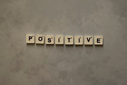 Scrabble tiles spelling 'Positive' on a textured surface, conveying optimism.