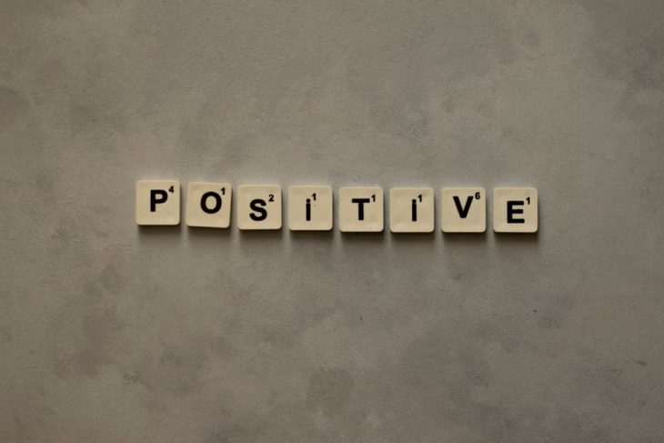 Scrabble tiles spelling 'Positive' on a textured surface, conveying optimism.